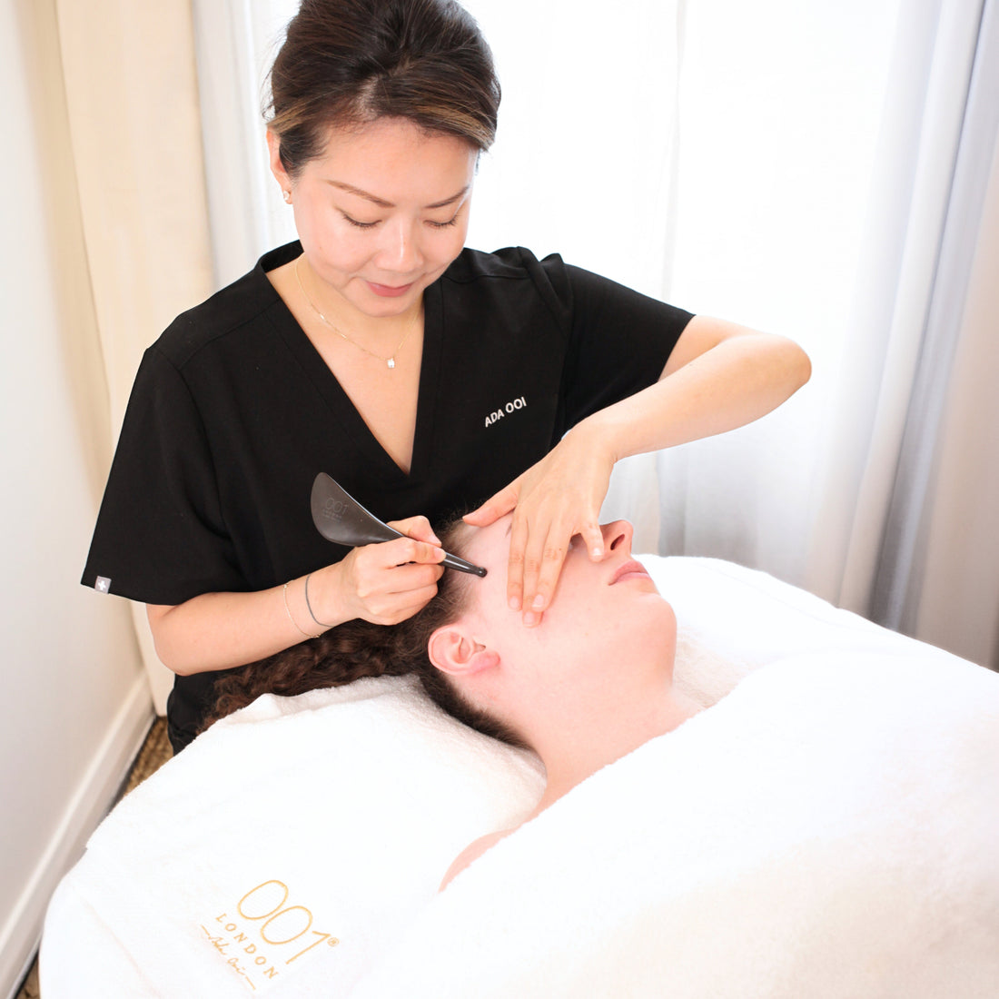 A skincare therapist performing a Gua Sha facial treatment on a model, using precise techniques to sculpt, lift, and rejuvenate the skin.